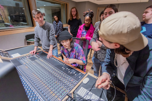 Students gather around the mixing board during Analog Recording class.