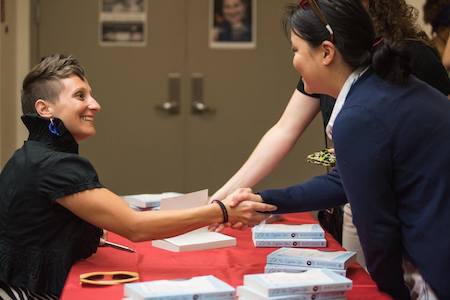Annie Liontas shakes hands with Creative Writing students over a table of books during the Visiting Writers Series.