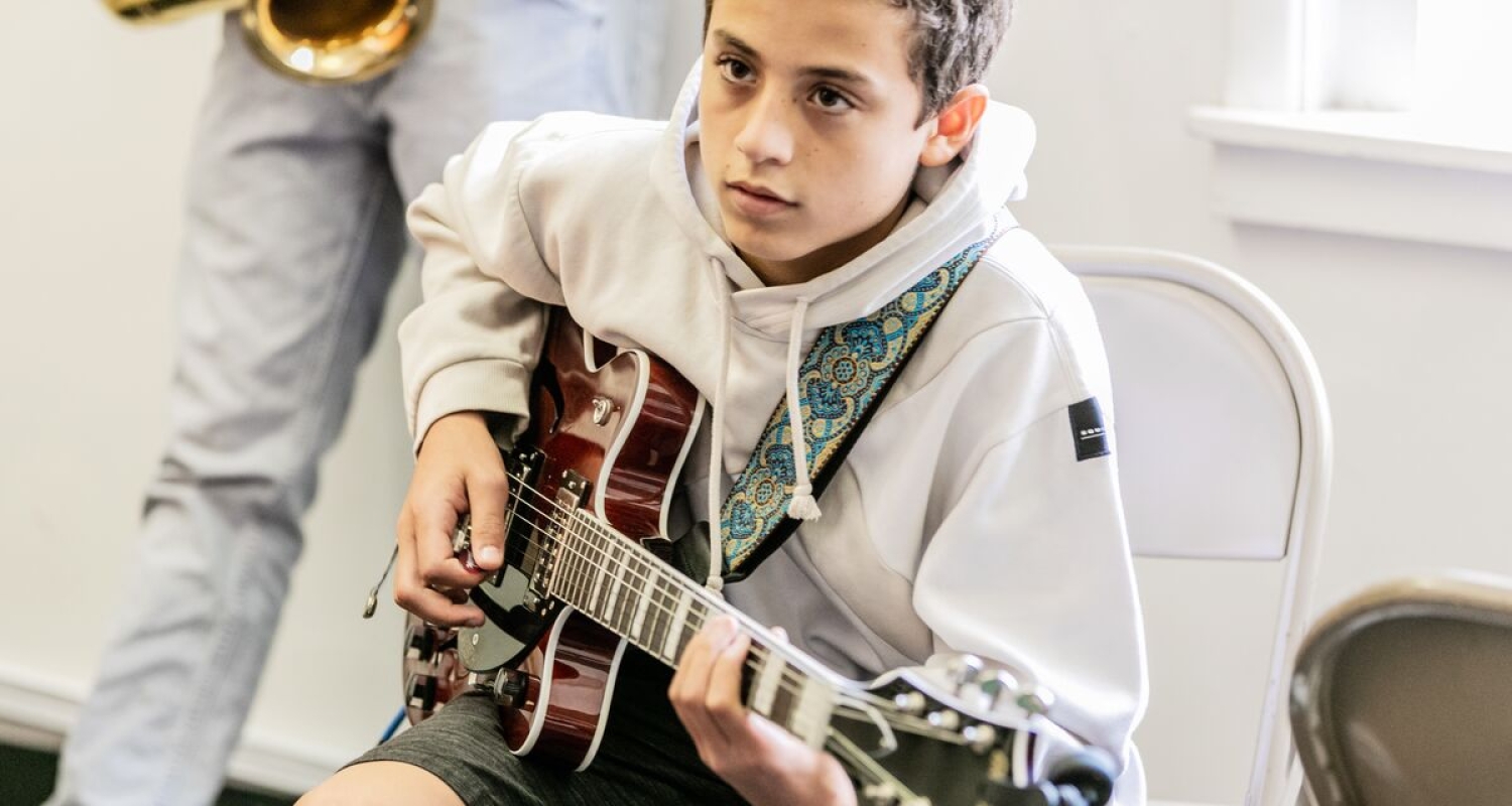 A student plays the electric guitar in a classroom