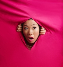 kristina wong poking her head through a slit in an expanse of hot pink fabric