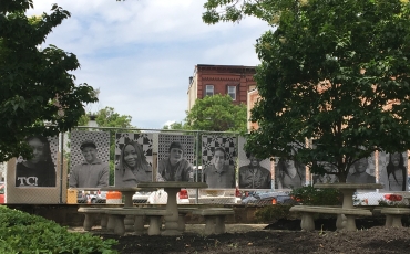 Black and white public portraits of some of the citizens of the city of Trenton in New Jersey that are hanging in a public outdoor green space 
