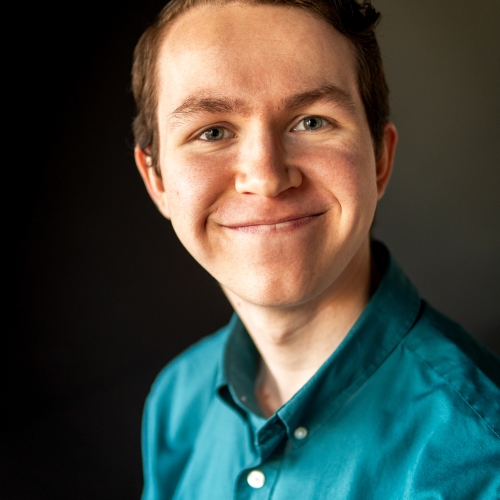 A smiling portrait of a person wearing a teal shirt