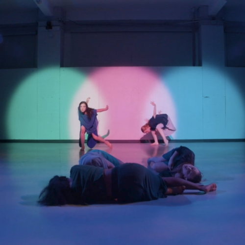 Students dance in a spotlit studio