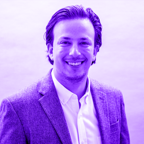 franklyn cantor overlaid with a violet hue. franklyn is wearing a blazer with a white collared shirt without a tie. he is smiling warmly, has slicked back hair, and is a touch scruffy.
