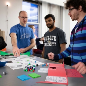 Three students discuss and play a game with dice during the Global Game Jam