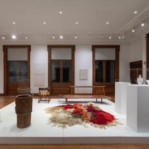  Invisible City Exhibition, Gallery B: raised platform in foreground displaying wooden furniture, pots, vases and a large fiber work  with large windows in the background
