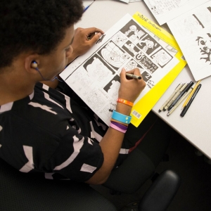 An art student works on their comic strip at their desk