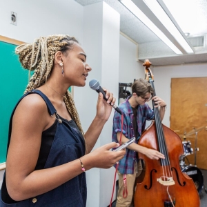 A singer and bassist rehearse in the classroom