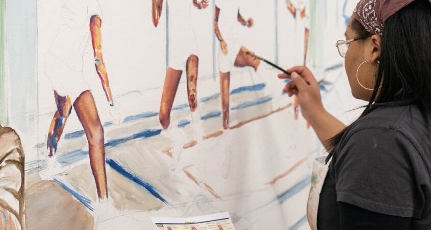 a student seen over the shoulder working on a painting depicting a row of bodies moving through poses