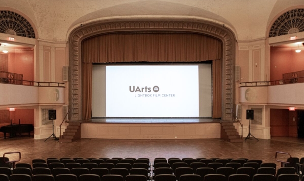 photo of an empty Levitt Auditorium with a white slide on the screen with UArts Lightbox Film Center logo