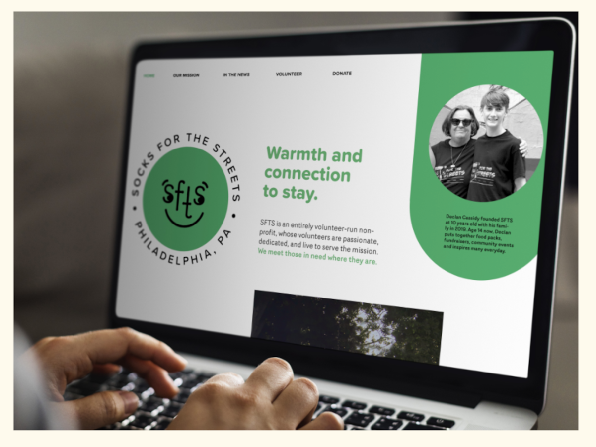 a depicting of a branding piece designed by lila nathanson. a mock-up of a website and phone screen are shown side by side, displaying branding identity for Socks for the Streets. at the left, a logotype of a smiley face with sock-like motifs is ringed by text. branding elements are in a pale emerald shade. 