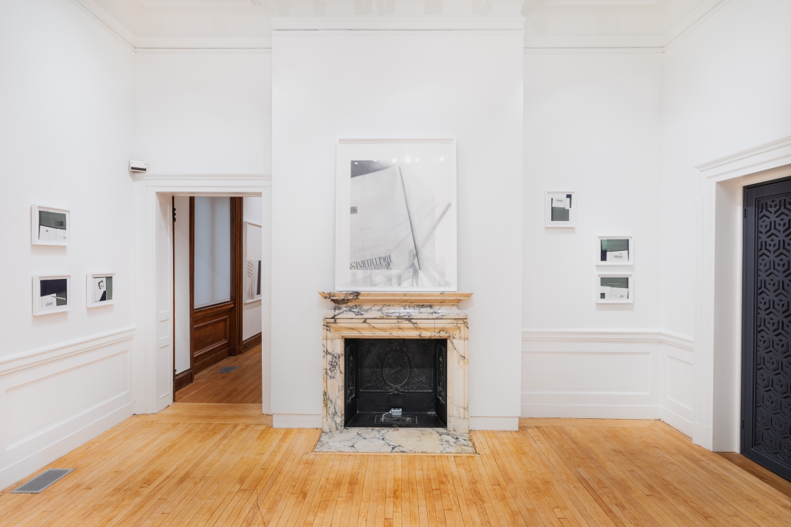 Installation shot of Nyeema Morgan's smaller framed collages hanging on walls in the left and the right of the space and a larger framed graphite drawing hangs above  in a gallery a prominent marble fireplace in the center of the photo. The gallery space features white walls and a wooden floor.