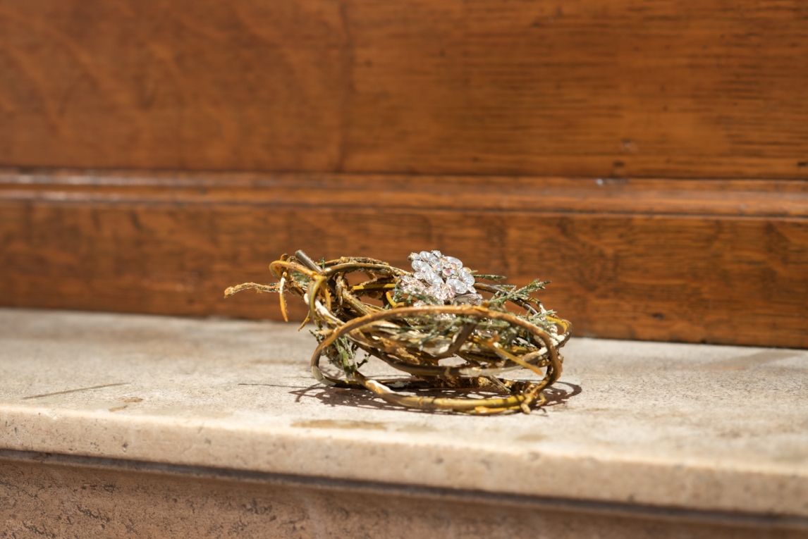  Nest of twigs with crystal costume jewelry piece sitting in center, displayed on mantle