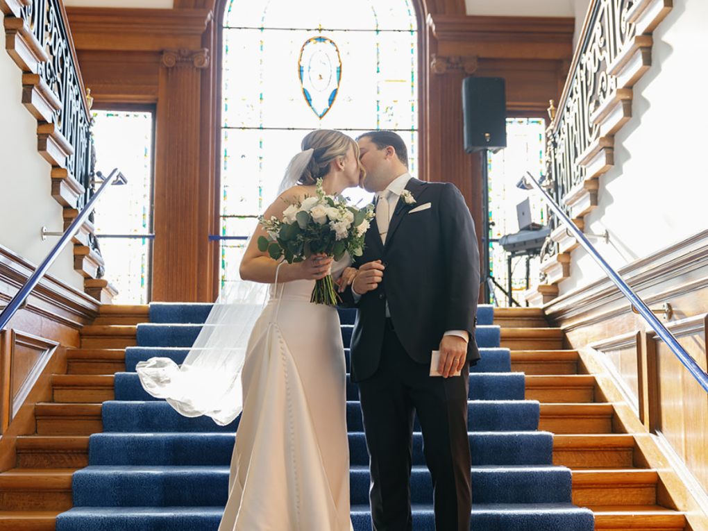 bride and groom sharing a kiss on the main staircase of the Philadelphia Art Alliance