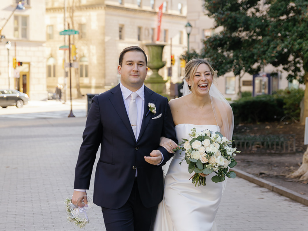 Bride and groom walking through Rittenhouse Square after wedding 