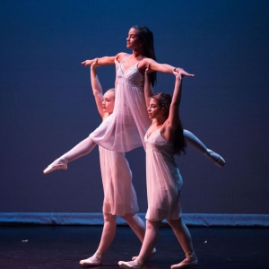 Two dancers lift another into the air during a performance